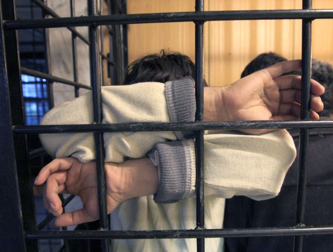 A detained illegal immigrant from a former Soviet republic waits in a holding cell at a police station in Russia's Siberian city.