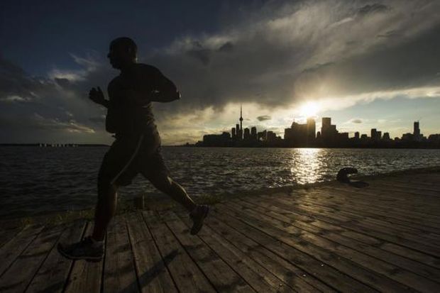 A man jogs in front of the skyline in Toronto.