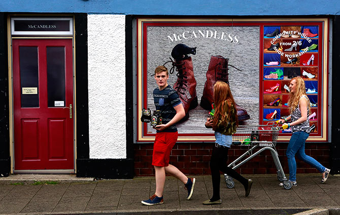 Youths walk past a shop, which has been covered with artwork to make it look more appealing, in the village of Bushmills on the Causeway Coast.