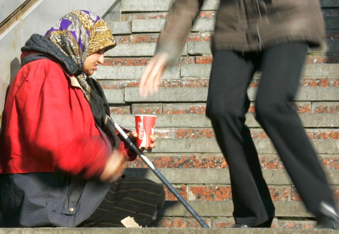 A person drops money into a container of a begging woman in Kiev.