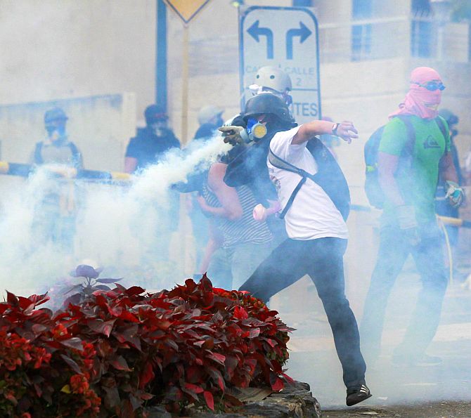 An anti-government protester throws a tear gas canister back at the police during a protest against the government.