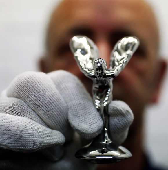 Worker Ronald Little poses with a finished Rolls-Royce mascot the Spirit of Ecstasy.