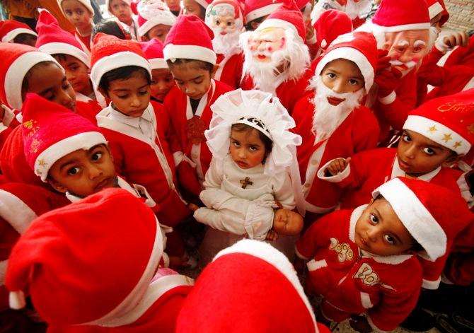 Children dressed in Santa Claus costumes gather around a girl dressed up as Virgin Mary during Christmas celebrations at a church in Chandigarh.