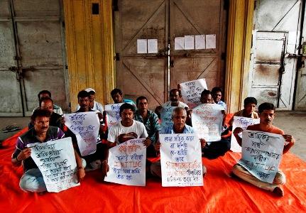 Employees hold placards as they sit on a protest outside Hindustan Motors Ltd's Uttarpara plant near Kolkata.