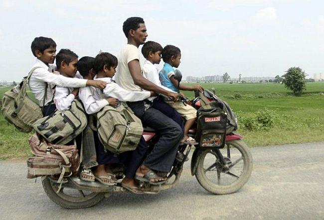 man rides a motorcycle carrying six children on their way back home from school at Greater Noida