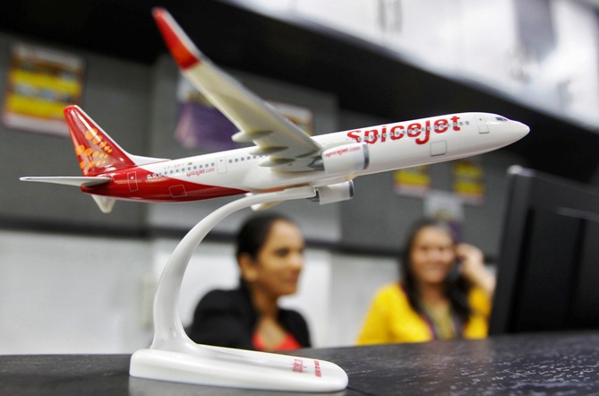 Employees work inside a travel agency office besides a model of a SpiceJet aircraft in Ahmedabad.