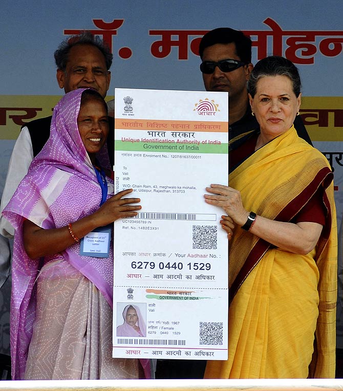 Chief of Congress party Sonia Gandhi (R) presents the 210 millionth biometric card to Vali , a villager residing in Rajasthan.