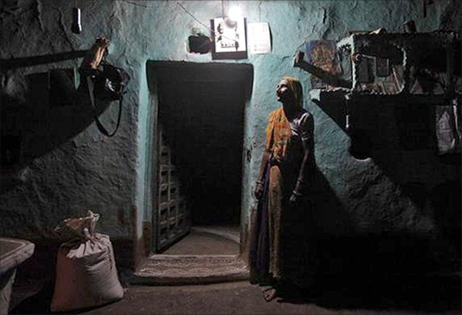 Sampat Bai, 64, poses for a picture inside her house illuminated by a Compact Fluorescent Lamp (CFL) that is powered by solar energy, at Meerwada village of Guna district, in Madhya Pradesh.