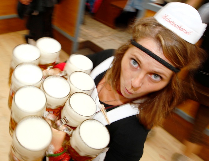 A waitress carries mugs of beer.