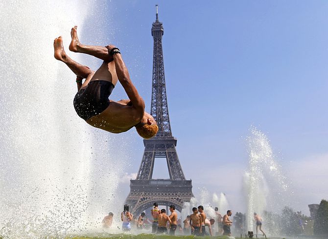 A man jumps in a fountain of the Trocadero Square in front of the Eiffel Tower, Paris.