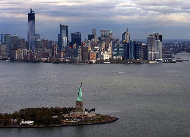 The Statue of Liberty and Liberty Island are seen in front of the Lower Manhattan skyline.