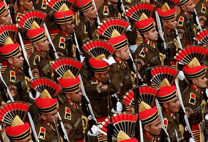 A policeman (C) adjusts his headgear as he marches with others during the full dress rehearsal for the Republic Day parade in New Delhi January 23, 2014. 