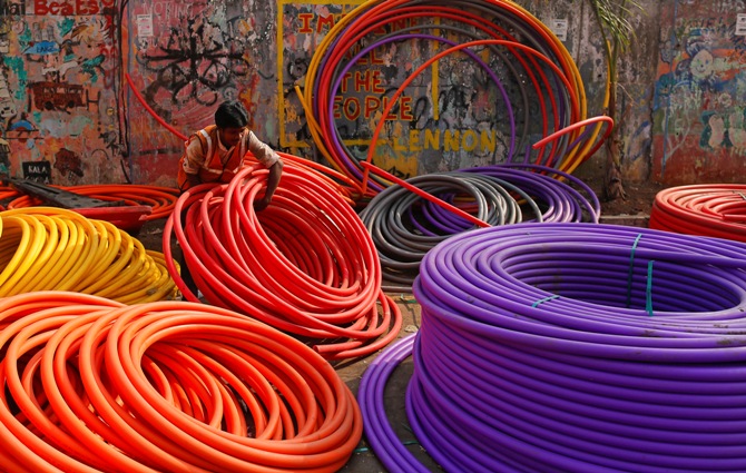 A labourer works amid rolls of underground telephone cable pipes on the side of a road in Mumbai.
