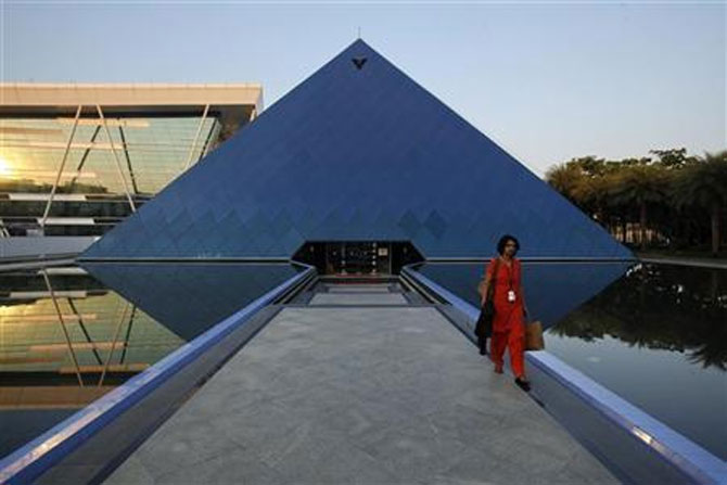  An employee walks out of an iconic pyramid-shaped building made out of glass in the Infosys campus at Electronics City in Bangalore.