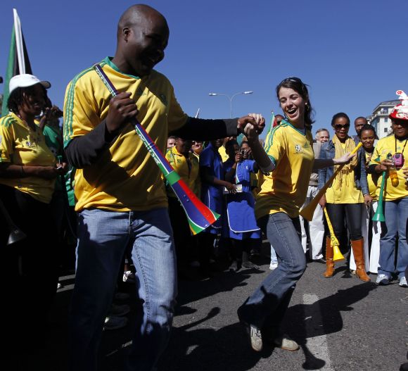 South Africans dance as they cheer during a parade to support the South African soccer team.