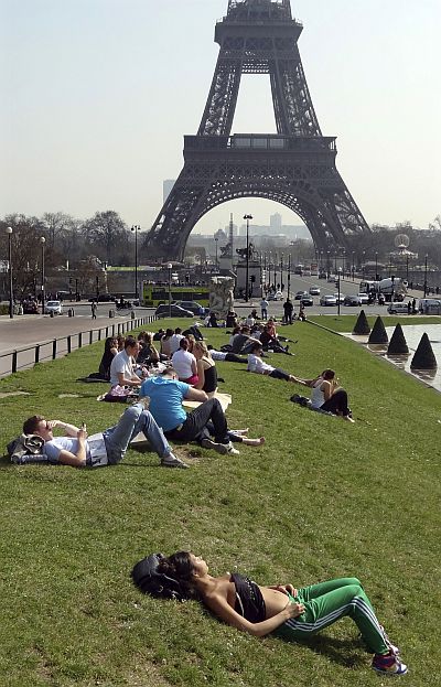People relax in the sun near the fountains at Trocadero square near the Eiffel tower.