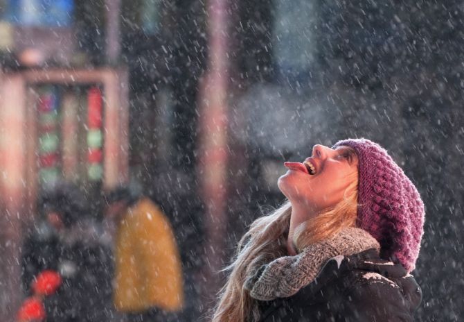 A tourist catches snowflakes on her tongue during snow fall in Times Square.