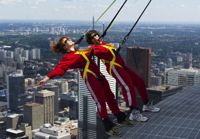 Reporters lean over the edge of the catwalk during the media preview for the EdgeWalk on the CN Tower in Toronto.