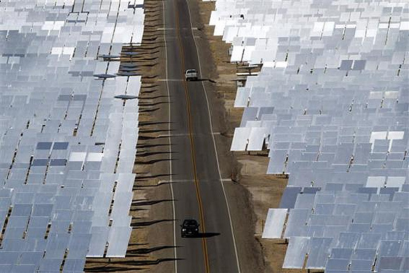 Vehicles drive through field of heliostats (mirrors that track the sun and reflect the sunlight onto a central receiving point) at the Ivanpah Solar Electric Generating System.