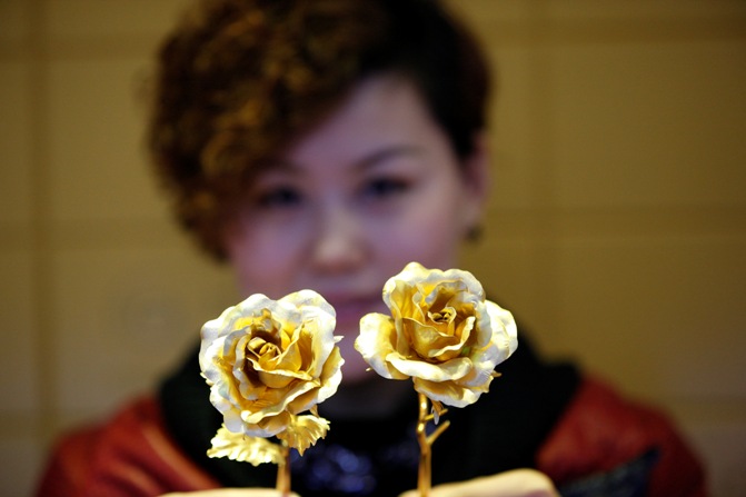 A woman holds golden roses on Valentines' Day at a gold store.
