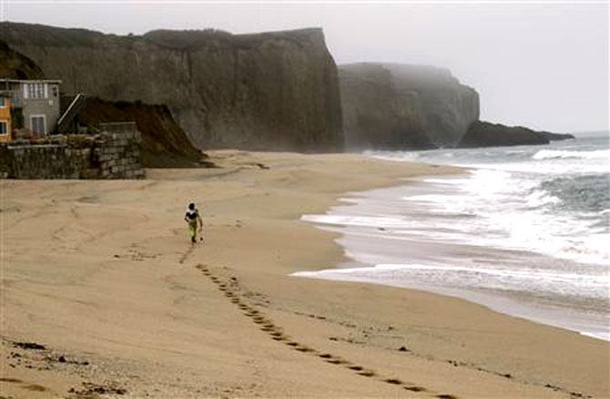 A surfer heads to a surfing spot at Martin's Beach, a popular surfing and fishing spot, in Half Moon Bay, California.