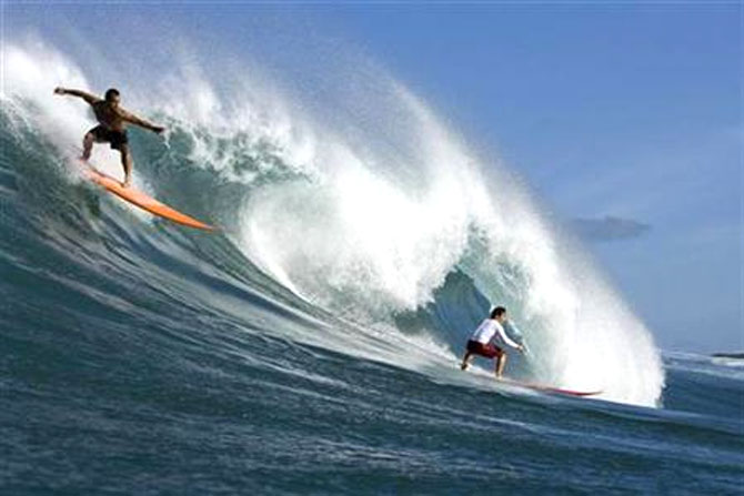 Surfers catch a wave.