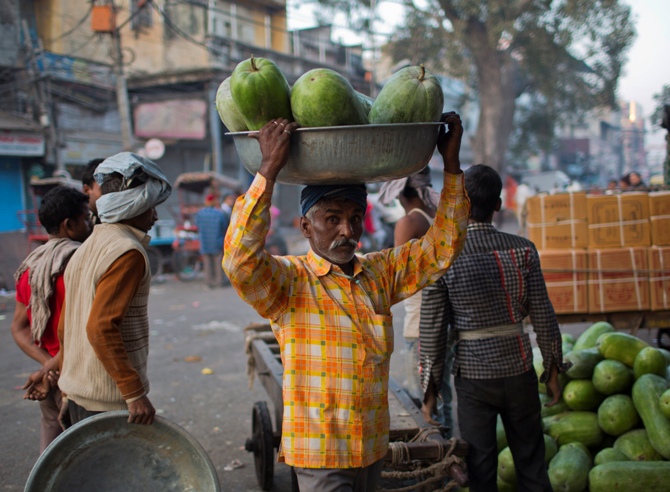 A labourer carries watermelons at a market early morning in the old quarters of Delhi.