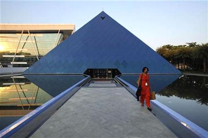 An employee walks out of an iconic pyramid-shaped building made out of glass in the Infosys campus at Electronics City in Bangalore.