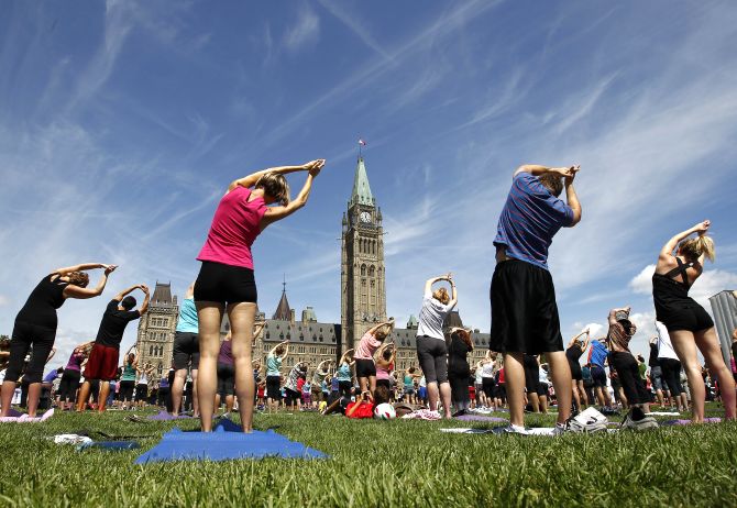 People take part in a free weekly yoga class on the front lawn of Parliament Hill in Ottawa.