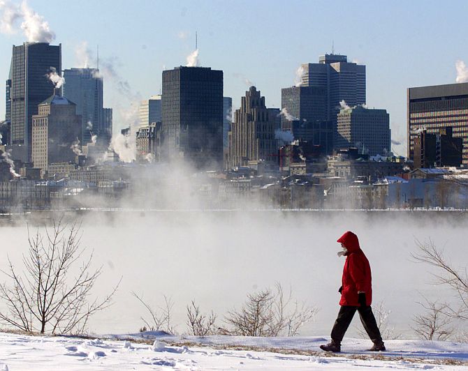 Ice fog rises from the St. Lawrence River as woman walks along the river bank in Montreal.