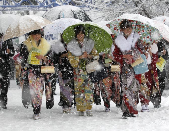 Japanese women in kimonos walk to attend a ceremony celebrating Coming of Age Day in heavy snowfall at Toshimaen amusement park in Tokyo.