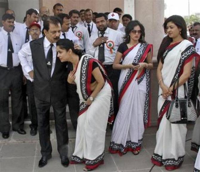 Subrata Roy (front, L) speaks with an employee. 