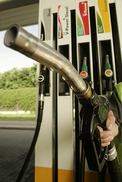 A worker holds a petrol pump nozzle.