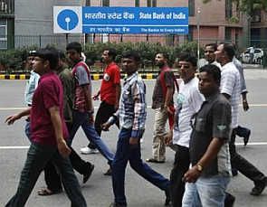 Commuters walk in front of the head office of State Bank of India in New Delhi 