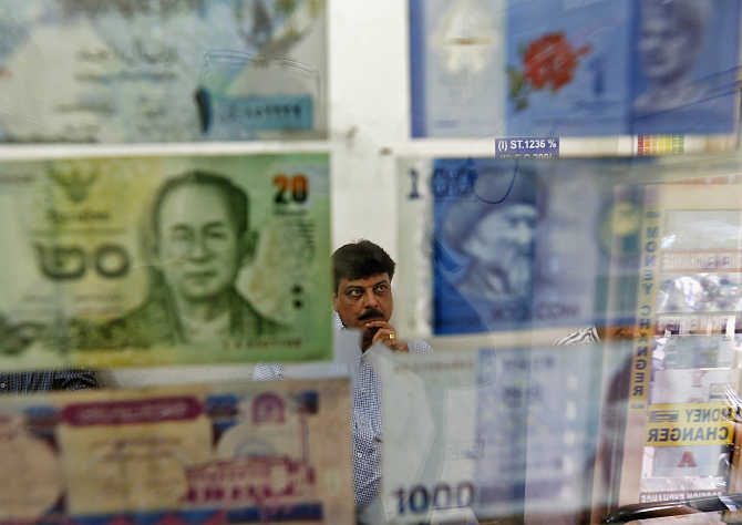 A man watches television inside his currency exchange shop in New Delhi.