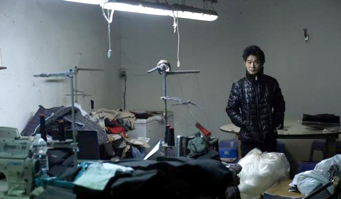 A Chinese immigrant looks on as police officers conduct a check at a textile factory in Prato.