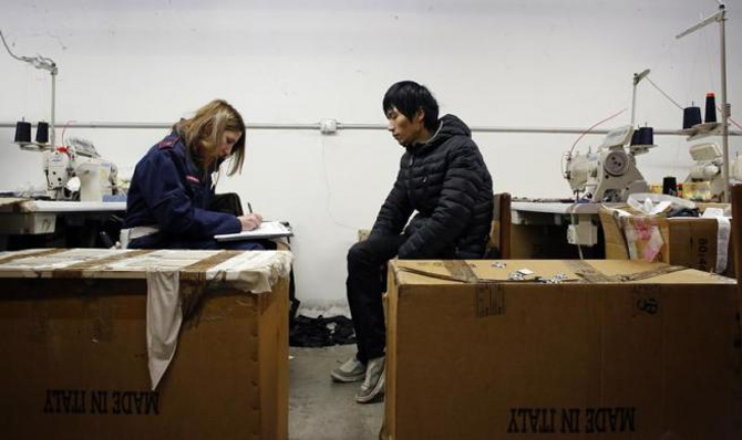  police officer checks the documents of a Chinese immigrant at the Shen Wu textile factory in Prato.