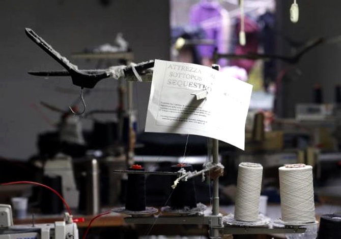 A paper that reads Equipment confiscated is seen on an industrial sewing machine as police officers conduct a check at the Shen Wu textile factory in Prato.