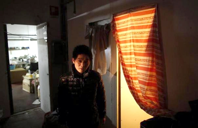 A Chinese immigrant stands near his room as police officers conduct a check at the Shen Wu textile factory in Prato.