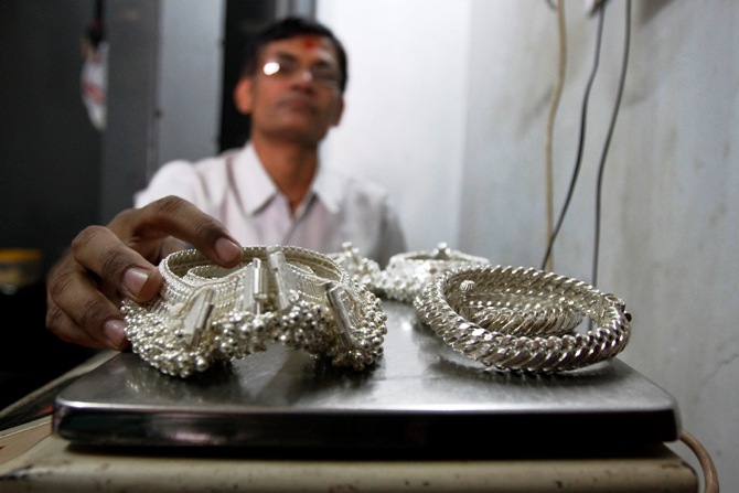 A silver trader weighs his silver ornaments inside his shop in Ahmedabad. 