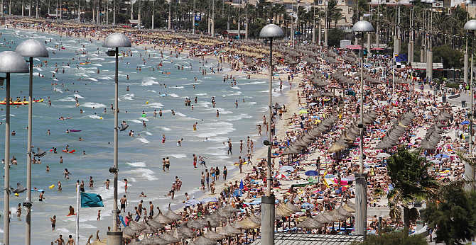 Tourists crowd Palma de Mallorca's Arenal beach in the Spanish Balearic island of Mallorca.