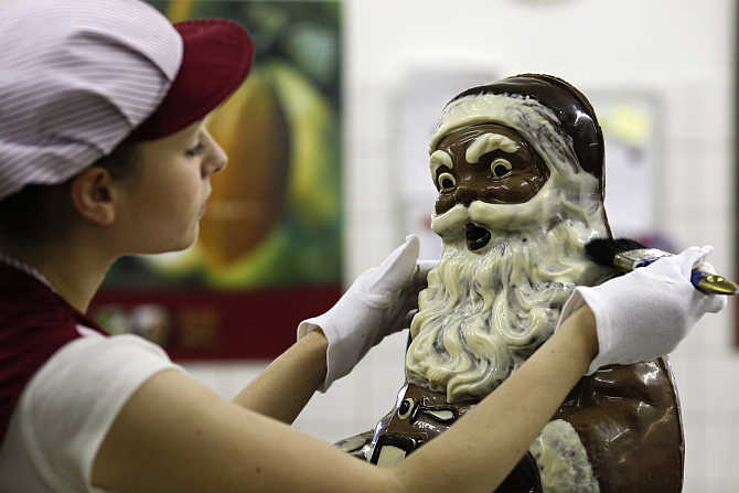 A confectioner makes final touches to a 90 centimetre high handmade chocolate Santa Claus figure, in the workshop of the Felicitas chocolate shop, in Hornow, south of Berlin, Germany.
