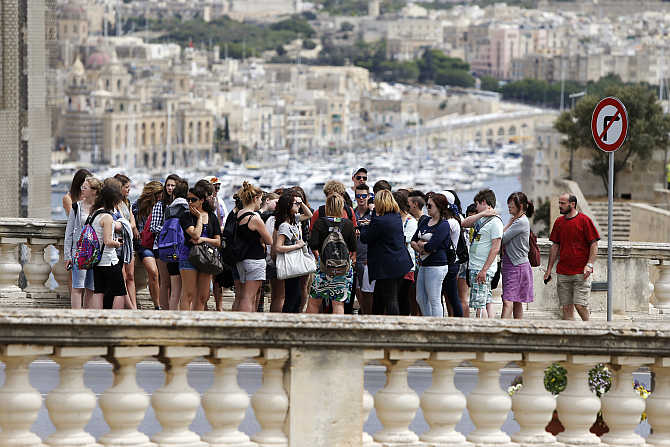 Tourists wait for a bus in Valletta, Malta.