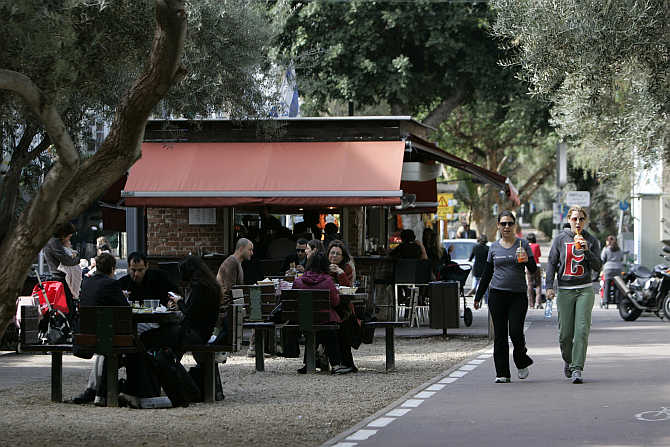 People walk past a cafe in Tel Aviv, Israel.