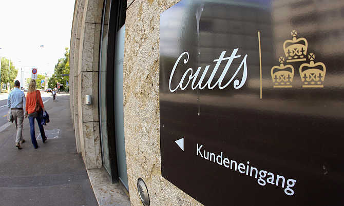 People walk past a sign marking the clients entrance of bank Coutts in Zurich, Switzerland.