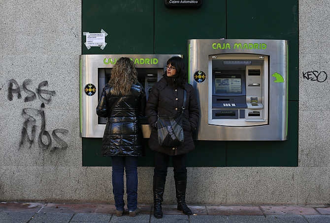 Women use an ATM at a Caja Madrid-Bankia branch in Madrid, Spain.