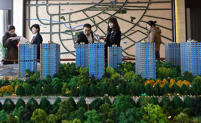Visitors look around a miniature of apartment complex at a showroom in Beijing.
