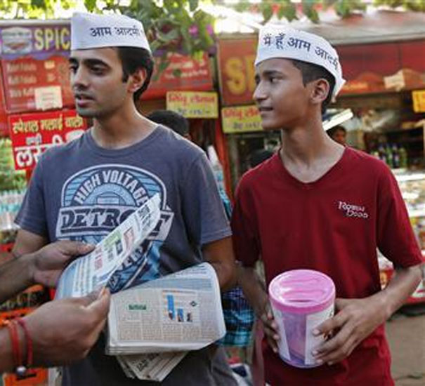 Aditya Gautam, 29, (C) and Sanskar Sharma, 12, (R), volunteers of Aam Aadmi Party campaign as they distribute party newsletters in the old quarters of Delhi.
