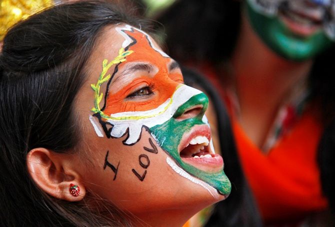 A girl, with her face painted in the colours of India's national flag, chants slogans