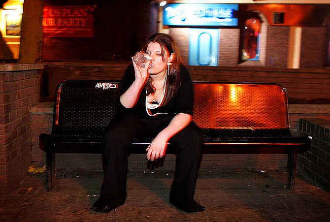 A woman drinks water after a night out in the Big Market area of Newcastle, England.